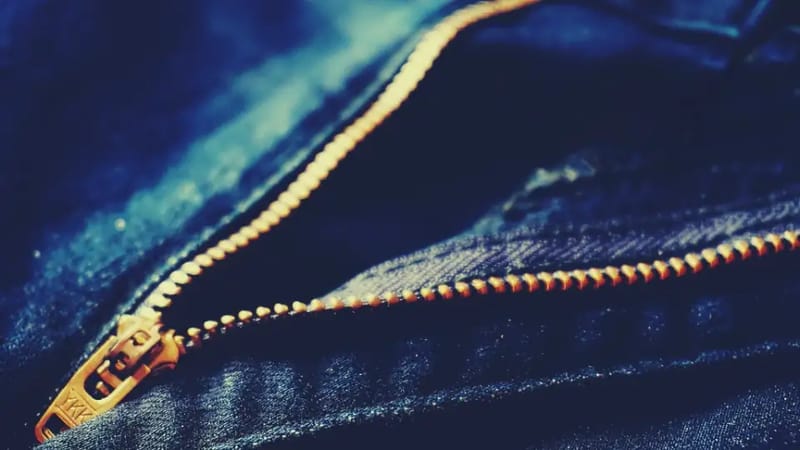 Goldener Metallreißverschluss auf blauem Jeansstoff