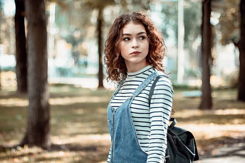 Frau im Ringelshirt und Latzhose im herbstlichen Park