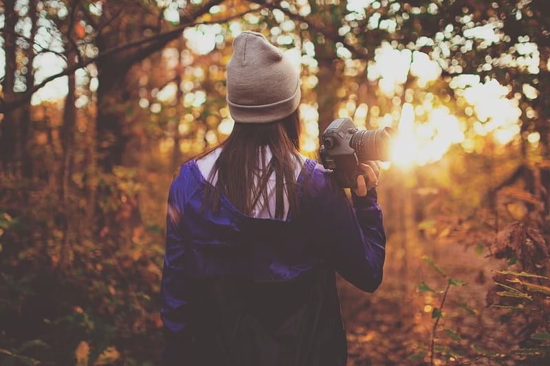 Frau mit sandfarbener Mütze im herbstlichen Wald