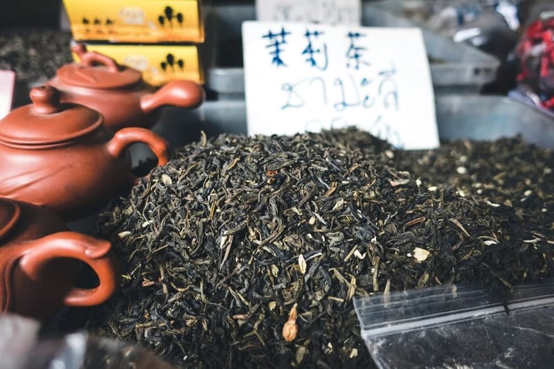 Loose black tea next to clay teapots