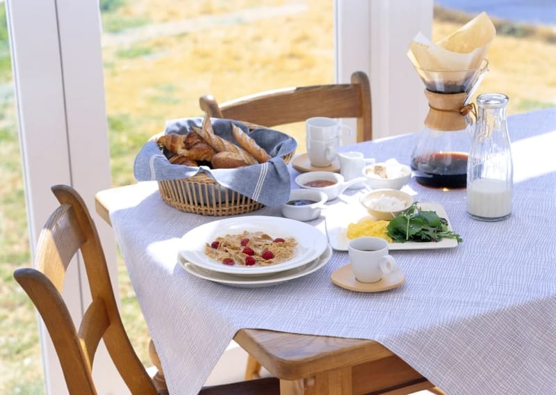 Gedeckter Frühstückstisch mit Kaffeekaraffe im Sonnenlicht
