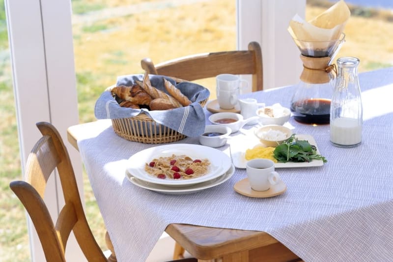 Gedeckter Frühstückstisch mit Kaffeekaraffe im Sonnenlicht