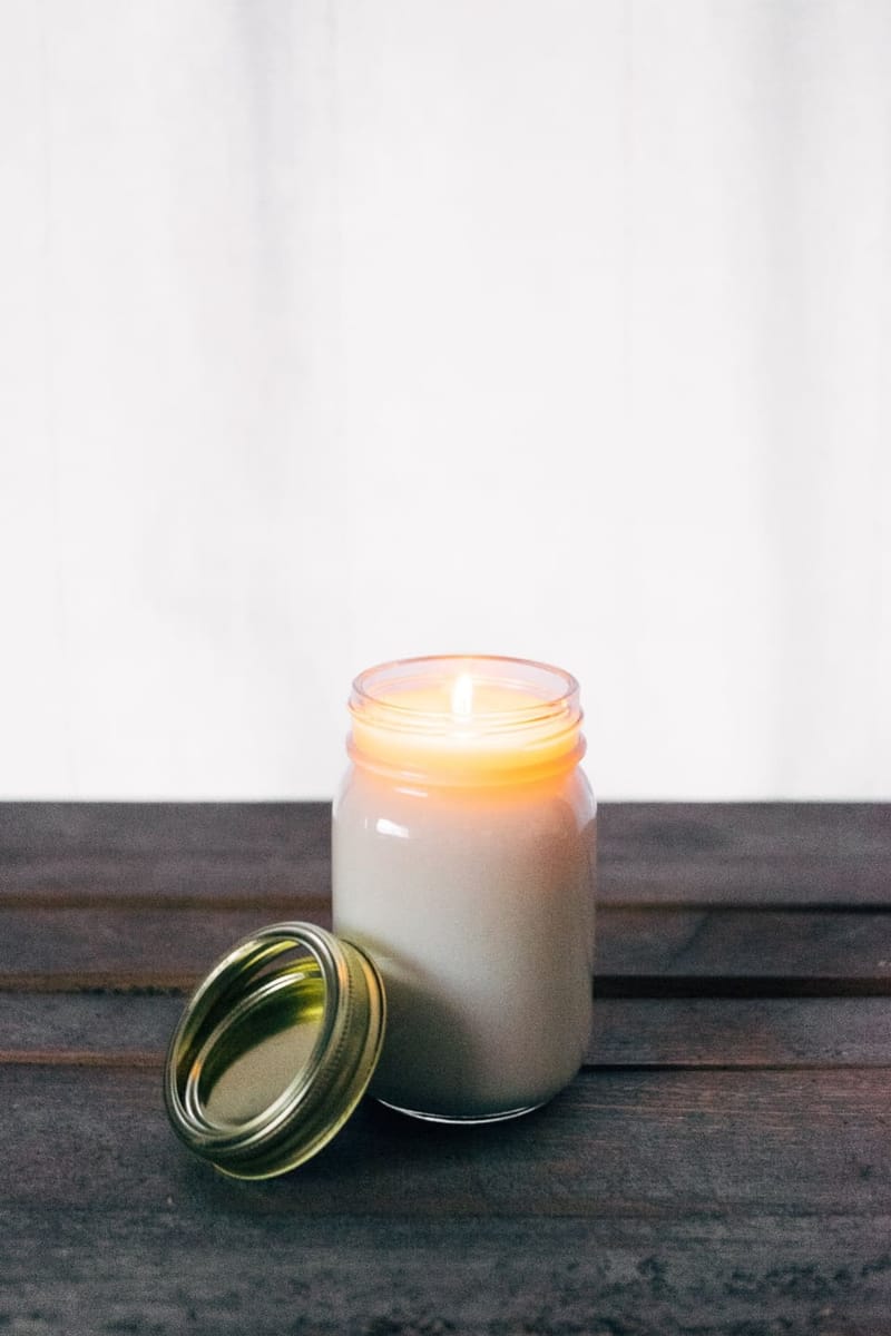 Weiße Duftkerze im Glas mit goldenem Deckel
