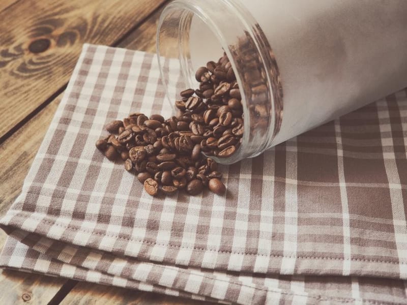 Kaffeebohnen aus einem Glas auf einem karierten Tuch