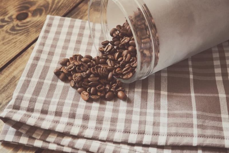 Kaffeebohnen aus einem Glas auf einem karierten Tuch
