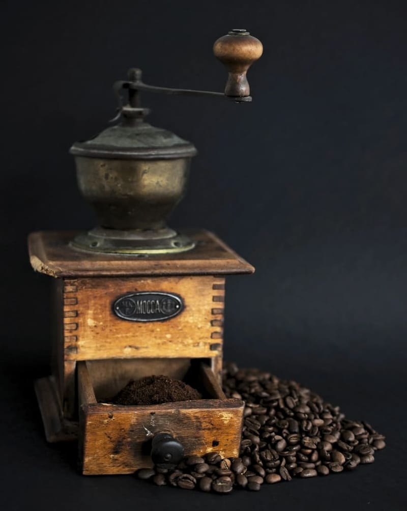 Wooden hand grinder with coffee beans on dark background