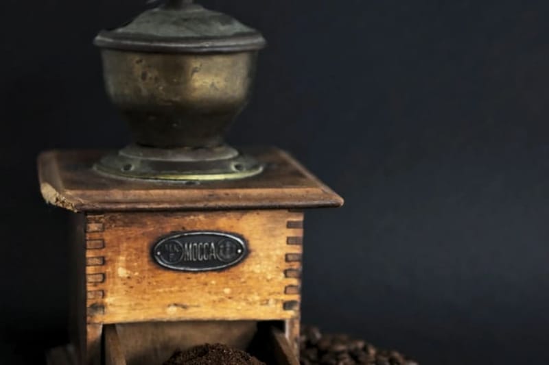 Wooden hand grinder with coffee beans on dark background