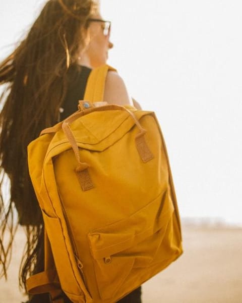 Woman with a mustard backpack in the wind