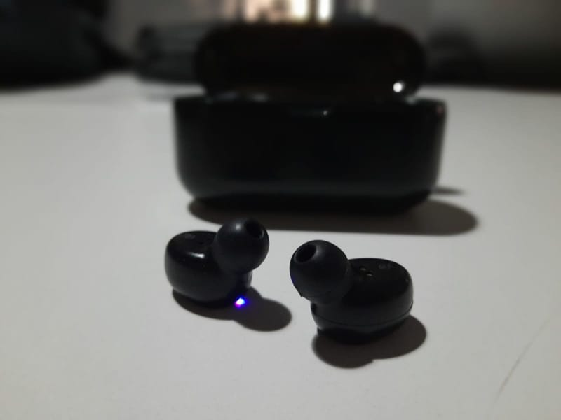 Schwarze In-Ear-Kopfhörer vor ihrem Ladecase