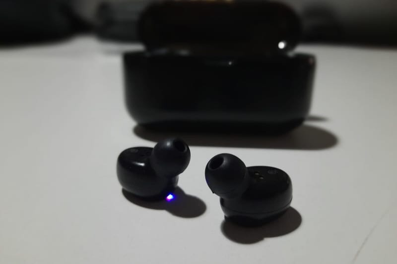 Schwarze In-Ear-Kopfhörer vor ihrem Ladecase