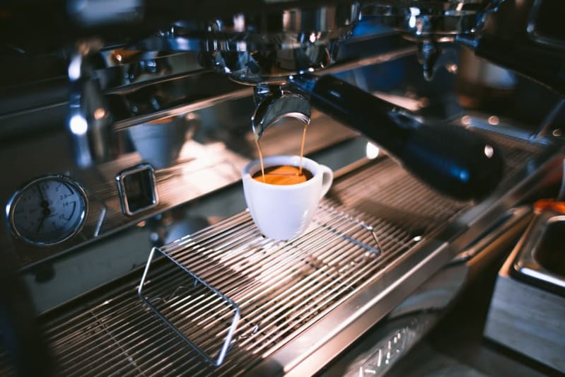 Espresso pouring into a white cup at the machine