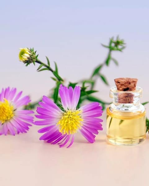 Kleine Ölflasche mit Korken neben Blüten