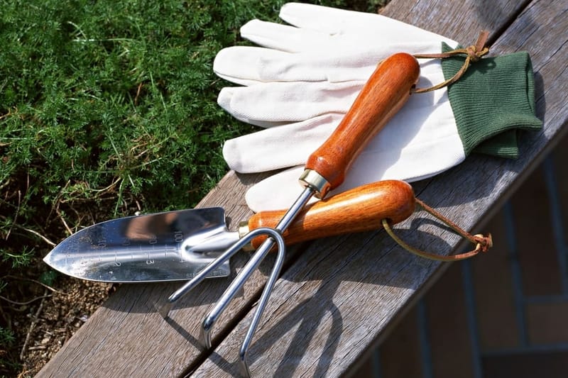 Handschuhe, Kelle und Grubber auf einer Holzbank