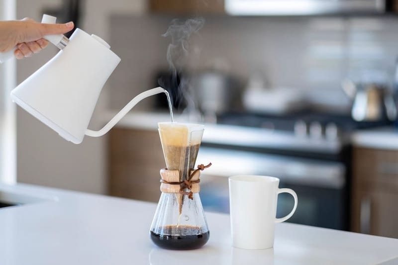 White gooseneck kettle pouring into a carafe