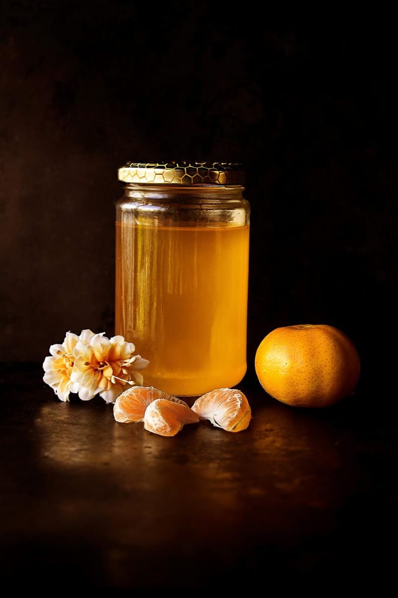 Honigglas mit Blüten und Mandarine