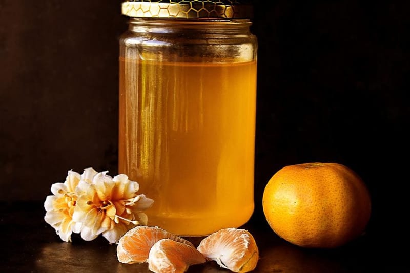 Honigglas mit Blüten und Mandarine