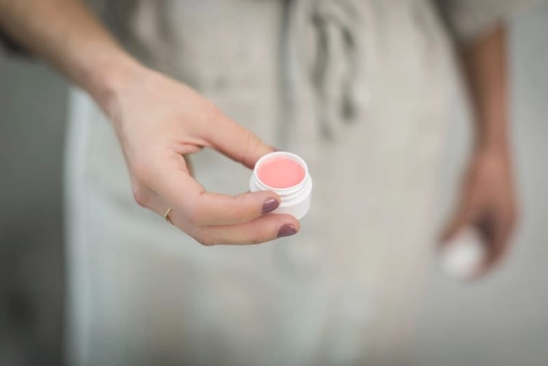 Hand holding a small balm pot