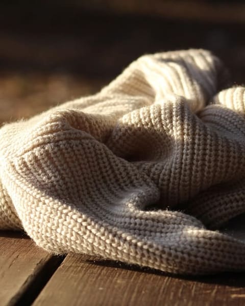 Naturweißer Strickpullover auf Holztisch