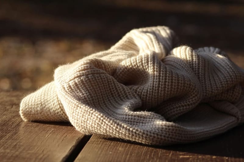 Naturweißer Strickpullover auf Holztisch