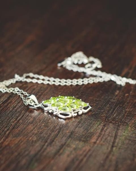 Silver necklace with peridot on dark wood