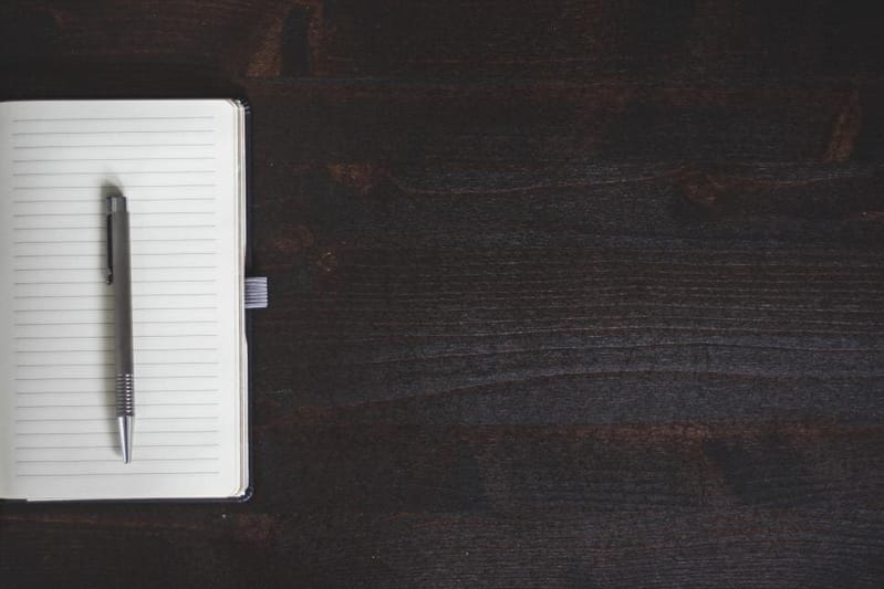Closed notebook with pen on dark wood