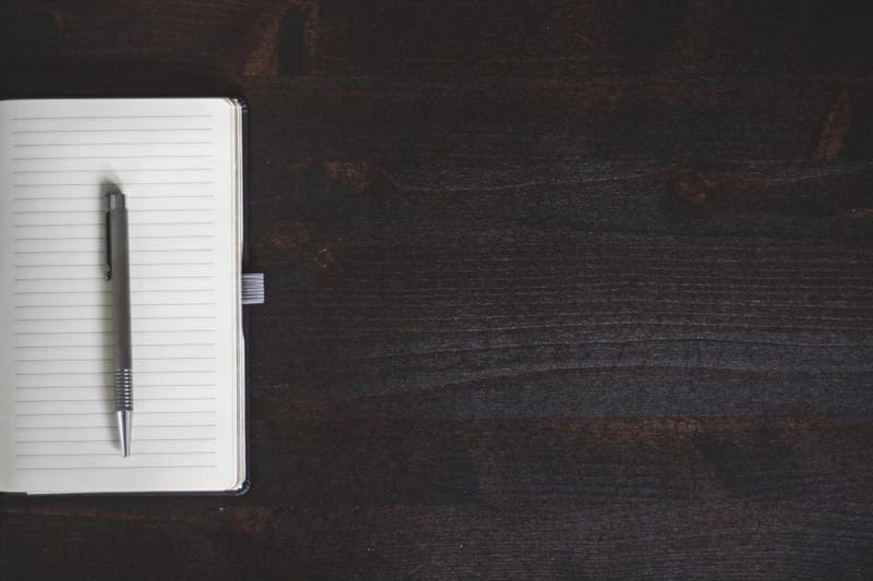 Closed notebook with pen on dark wood