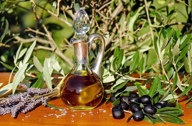 Carafe of olive oil with olives and branches