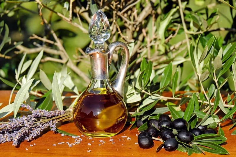Carafe of olive oil with olives and branches