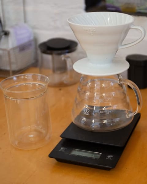 Weißer Handfilter auf einer Glaskanne und Waage