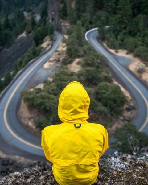 Person in a yellow rain jacket above a winding road