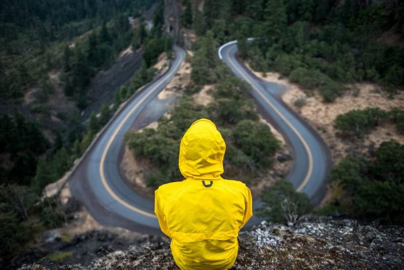 Person in a yellow rain jacket overlooking a winding road