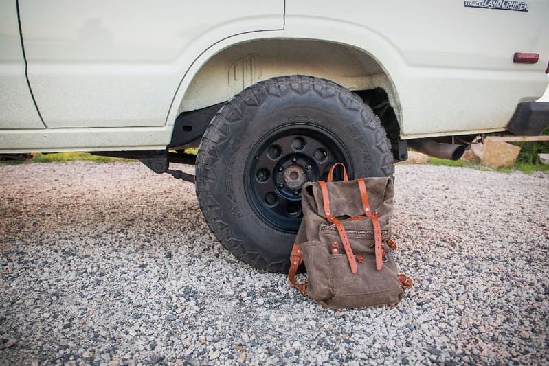 Rucksack vor dem Rad eines Geländewagens