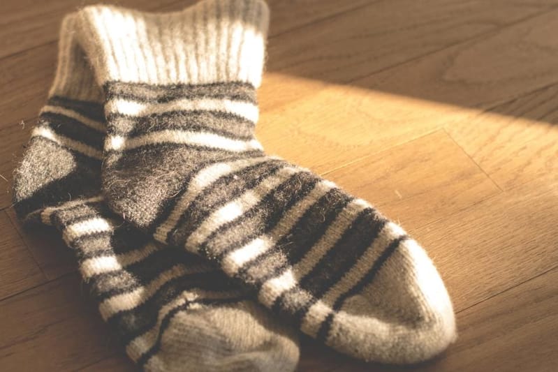 Grau-natur geringelte Socken auf Holzboden