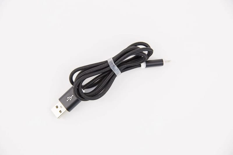 Schwarzes, textilummanteltes USB-Kabel vor weißem Hintergrund
